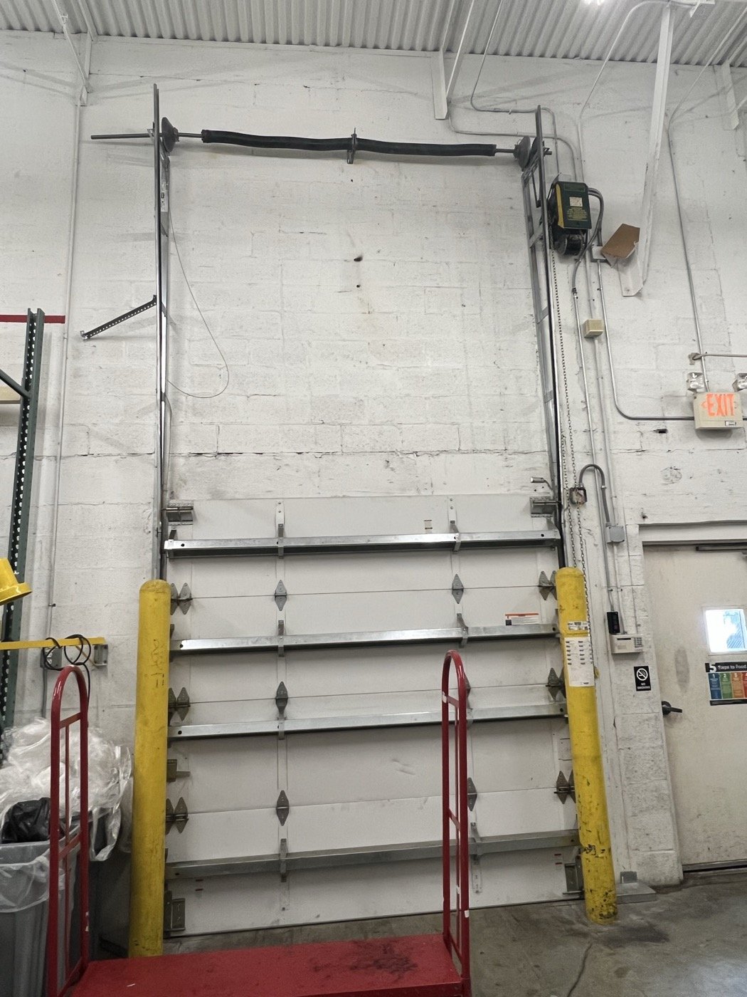 Commercial sectional overhead door with high-track hardware and wall-mounted operator