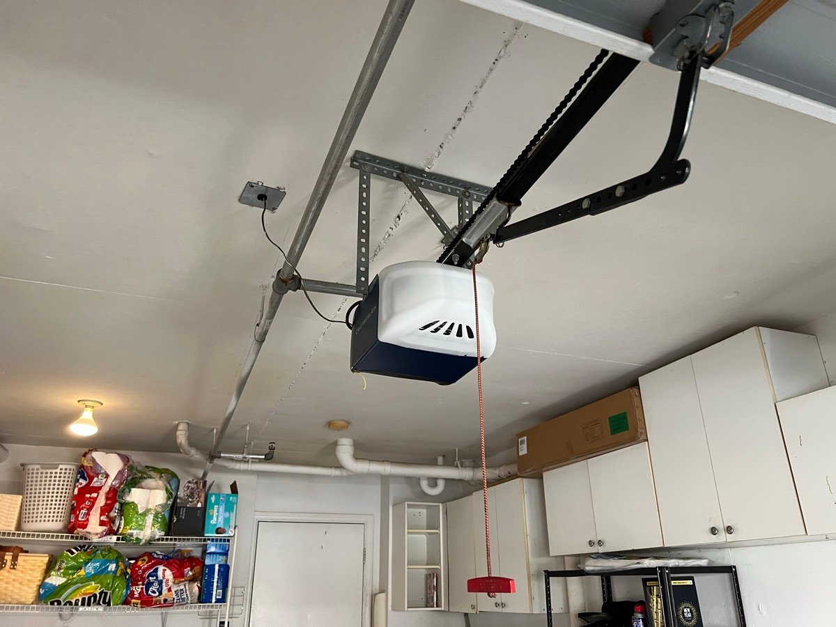 Ceiling-mounted garage door opener connected to a sectional door