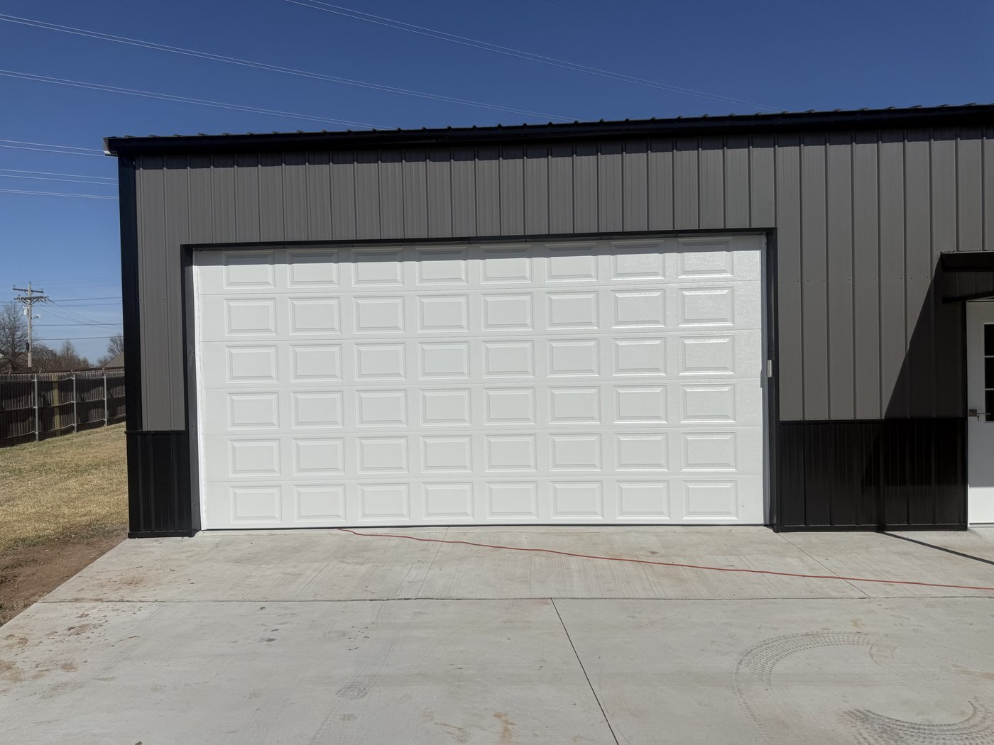 White sectional overhead door installed in a dark metal building