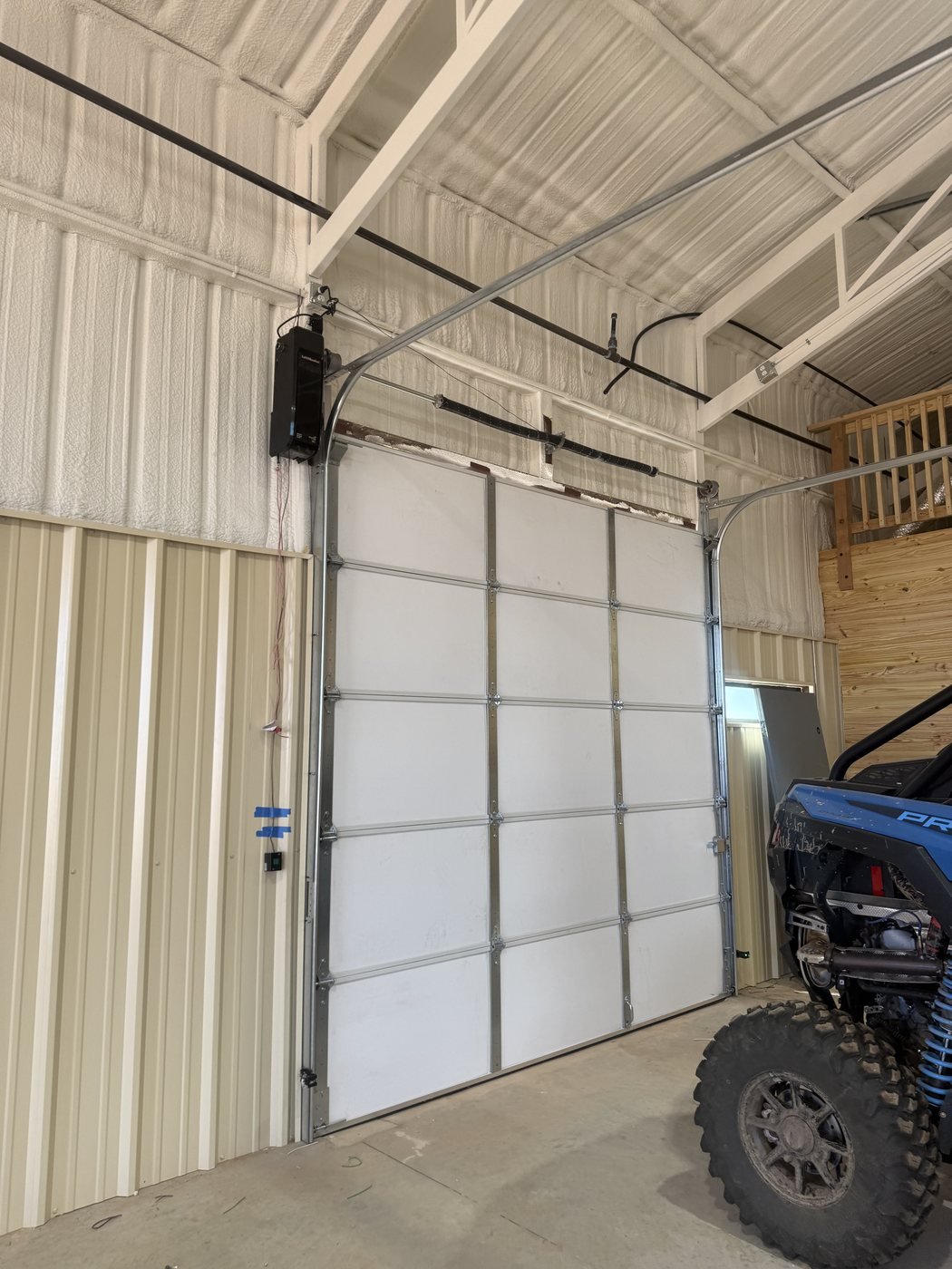 Tall white sectional overhead door inside a metal building