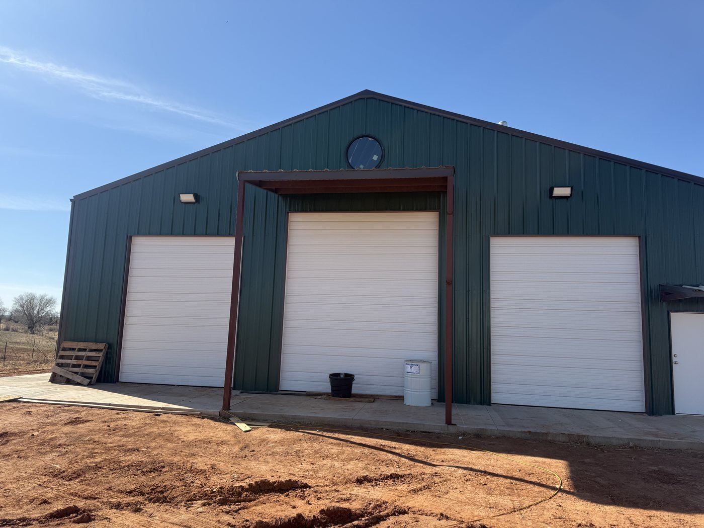 Metal commercial building with three white overhead door openings