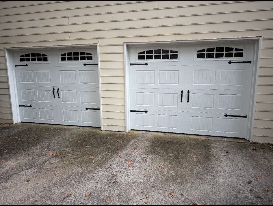 Two white carriage-style sectional garage doors with arched windows at a Longmont project