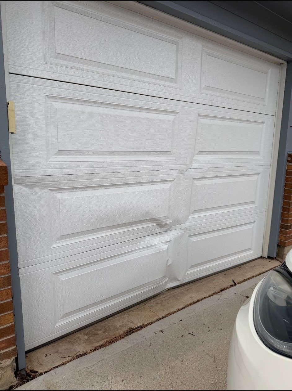 White raised-panel garage door with deep creases across several sections at a Lyons project