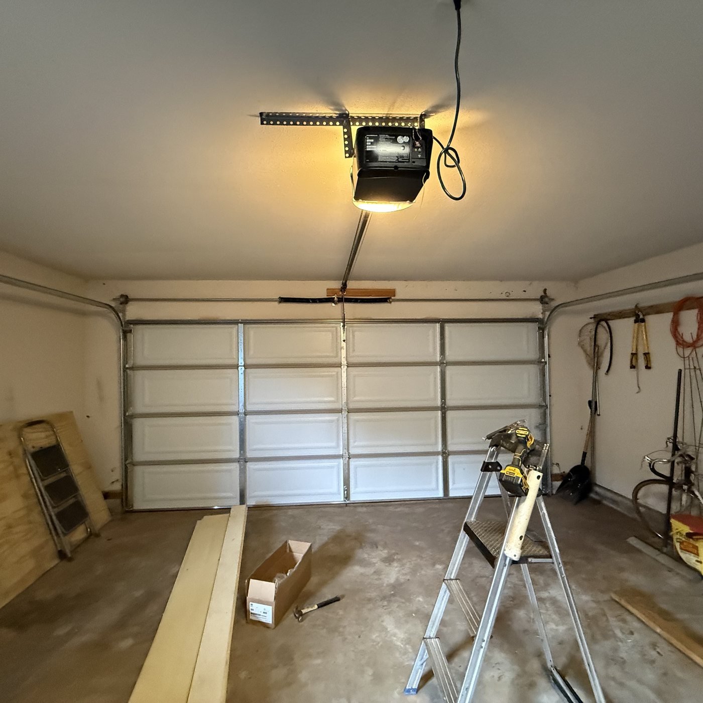 Ceiling-mounted garage door opener above a sectional door and work area