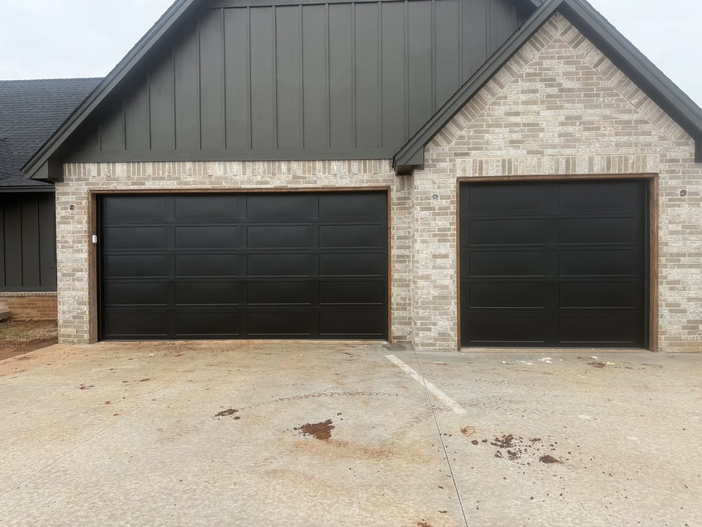 Black double garage door and matching single garage door on a brick home
